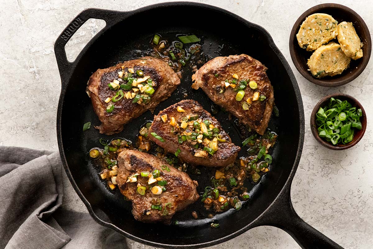 Four steak fillets in a cast iron skillet.