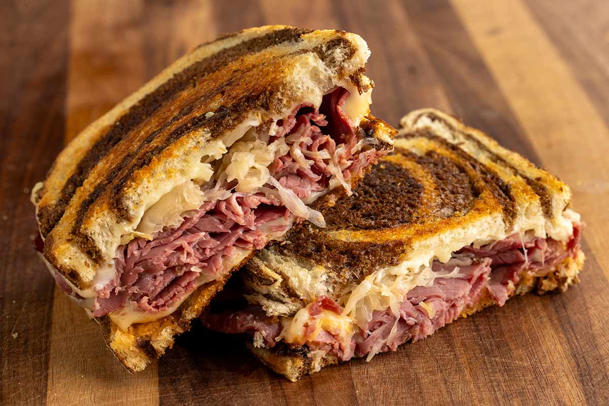 Reuben sandwich cut in half showing the corned beef, sauerkraut, and melted swiss cheese inside.