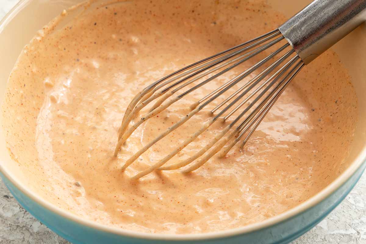 Russian dressing in a bowl with a whisk.