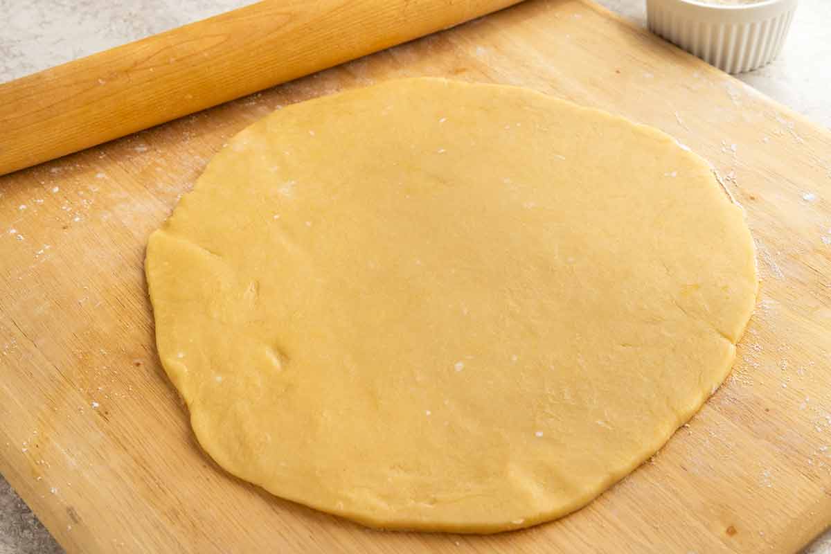 Tart crust dough rolled out on a wooden surface.
