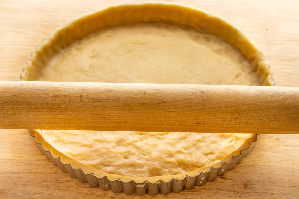 Rolling pin flattening the edges of a tart pie dish.