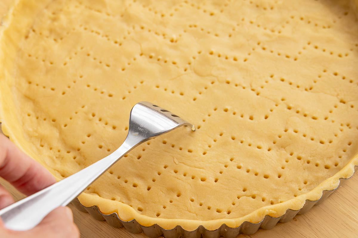 Metal fork making holes into a crust.