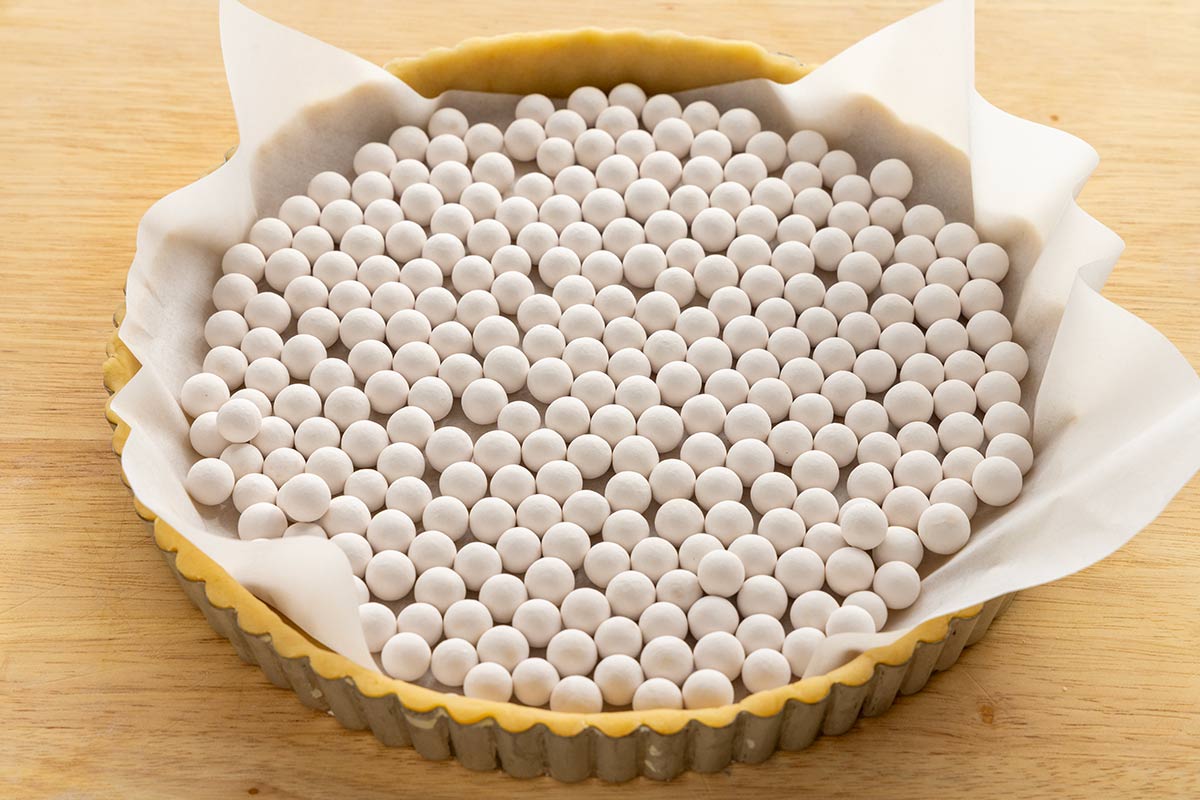 Pie weights laying on top of a tart crust.
