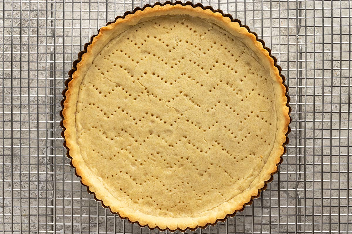 Baked tart crust cooling on a wire rack.