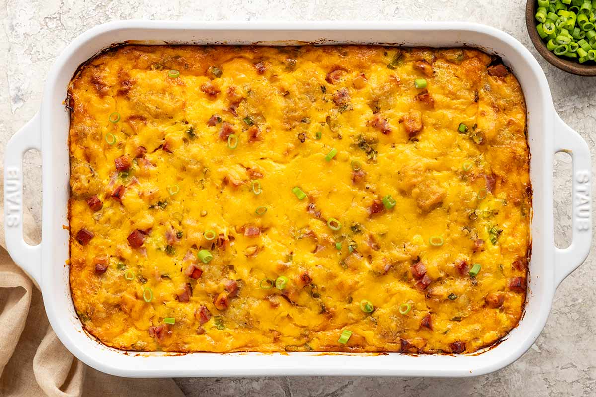 Cheese, ham, and egg breakfast made in a white casserole dish.