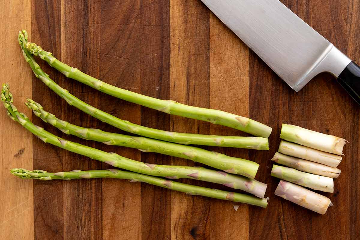 Asparagus on a cutting board with the thick ends sliced off.