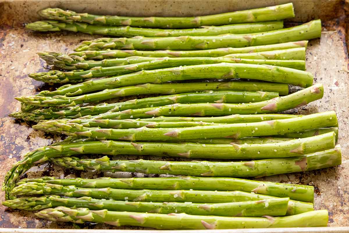 Asparagus spears on a roasting pan before going in the oven.