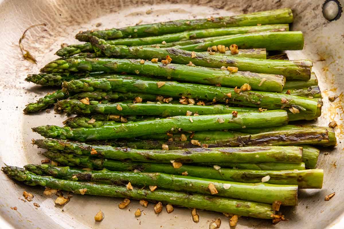Asparagus cooked in a pan with minced garlic.