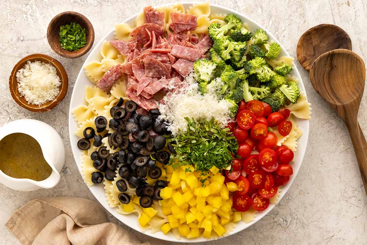 Bowl of broccoli, olives, tomatoes, and salami.