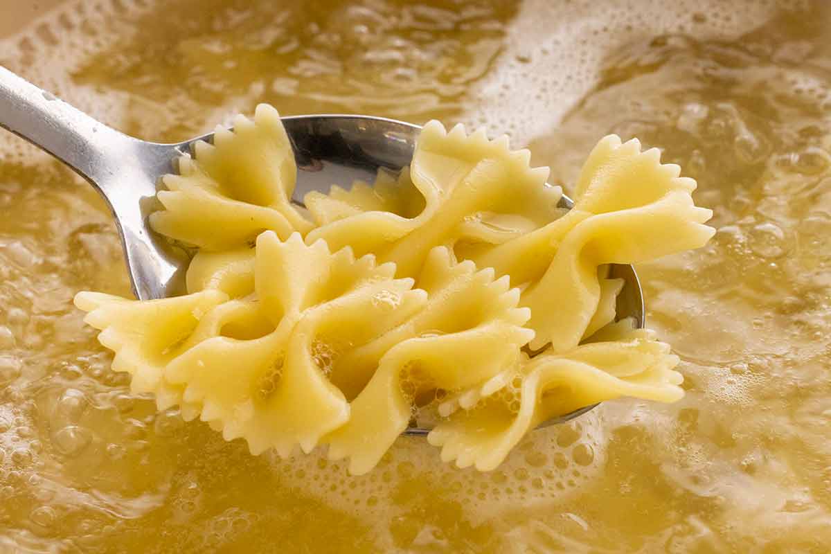 Bow tie pasta cooking in a pot of boiling water.