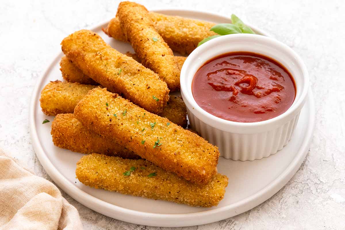 Plate of mozzarella cheese sticks served marinara sauce.