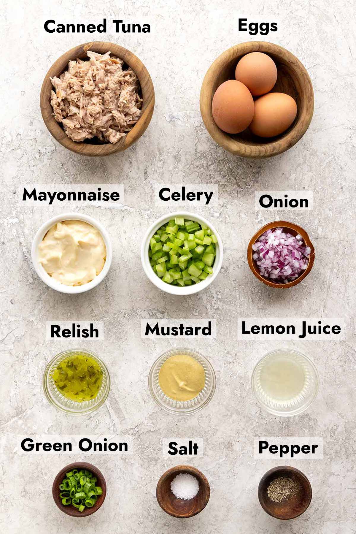 Bowl of tuna, hard boiled eggs, mayo, celery, red onions, and more salad ingredients.