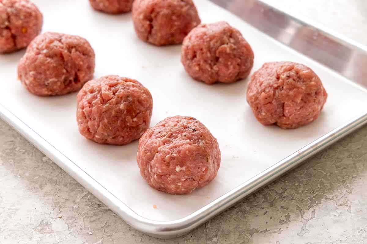Raw breakfast sausage mixture rolled into balls on a parchment-lined baking sheet