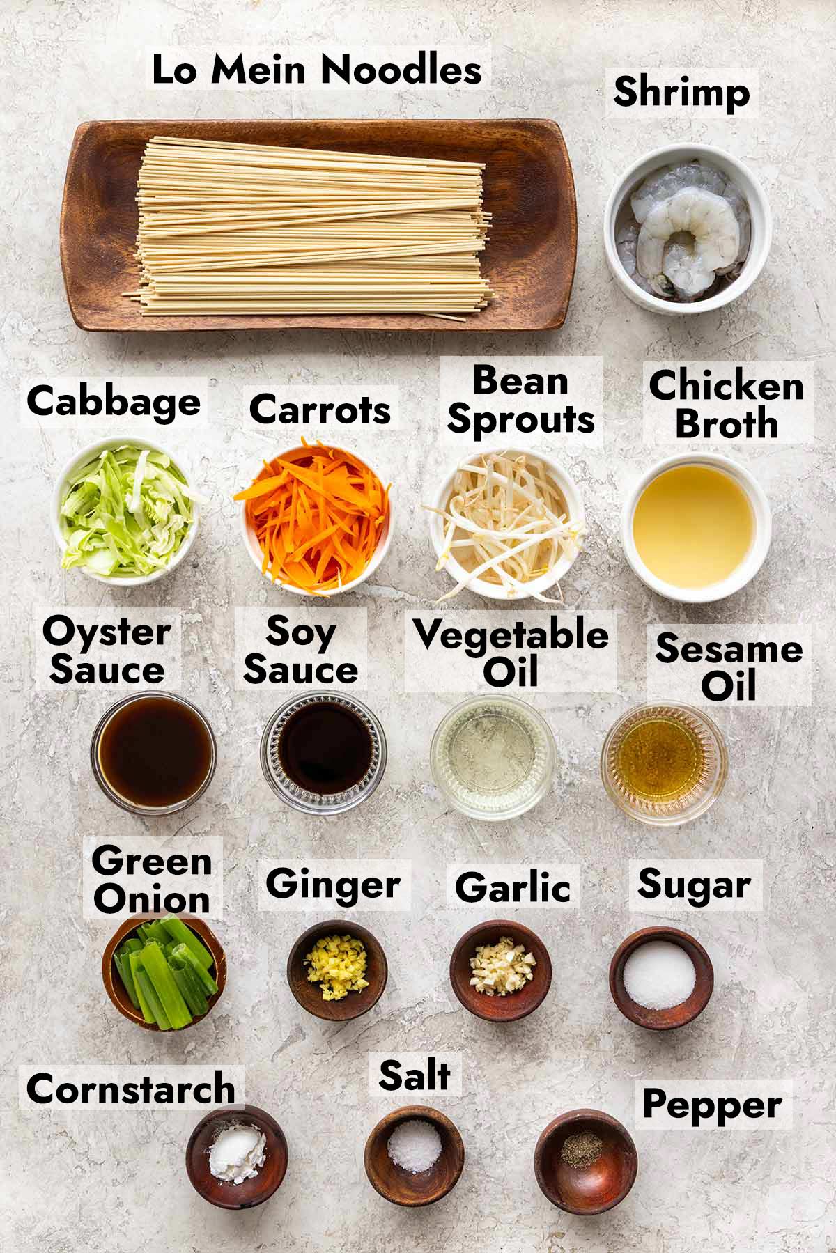 Bowls of Lo mein noodles, shrimp, cabbage, carrots, sauces, green onions, and other ingredients,