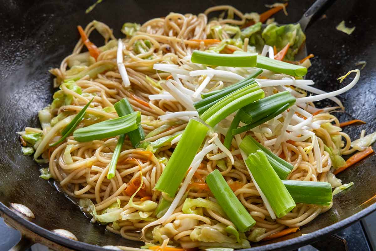 Pieces of bean sprouts and green onions added to a stir fry.