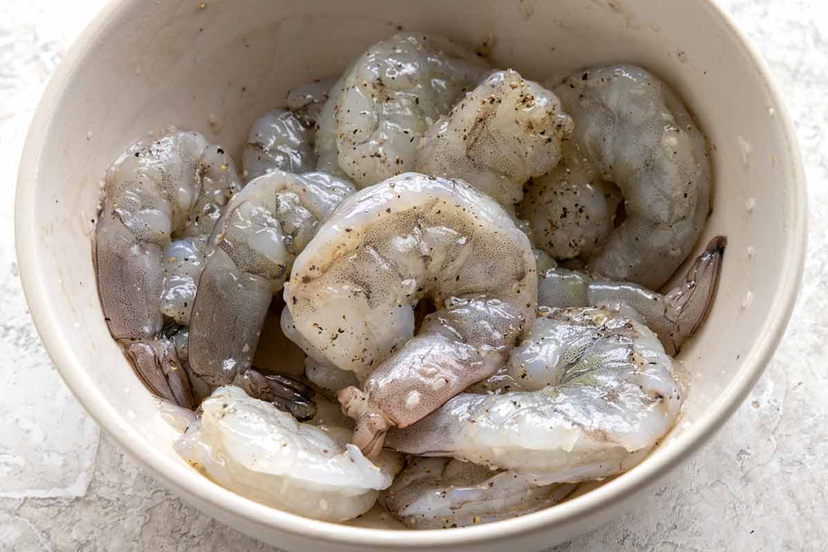 Raw shrimp marinating in a mixing bowl.