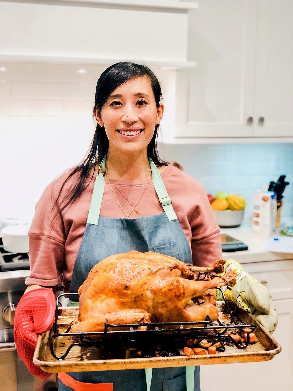 Jessica Gavin holding a roast turkey on a rack in her kitchen.